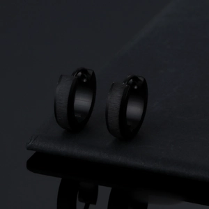 Detail of matte black titanium steel hoop earrings with brushed metal finish and reflection