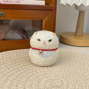 Detailed view of a hand-carved style cat figurine with red collar and golden bell