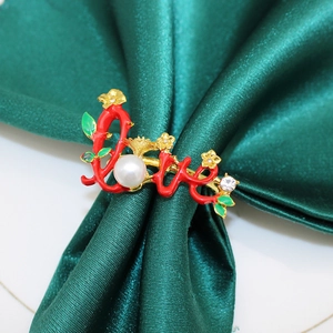 Detailed view of cursive LOVE rose napkin ring with red enamel and pearl on green silk