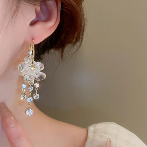 Dettaglio degli orecchini a fiore con nappa di strass indossati da una modella