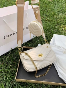 Cream quilted crossbody bag with gold chain and matching coin purse on green grass