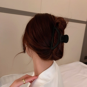 Pince à cheveux géométrique noire mate vue de dos sur les cheveux d'un modèle