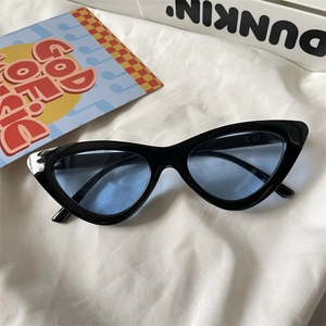 Close-up of retro cat-eye sunglasses with black frame and sky blue lenses on white cloth