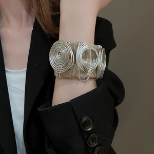Detail of wide spiral woven silver cuff bracelet with artistic tiered metal discs