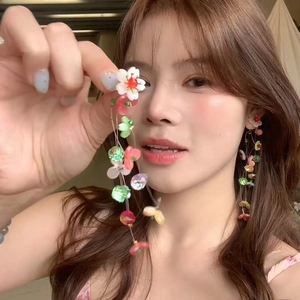 Close-up of handmade colorful floral tassel earrings worn by a model in a casual setting