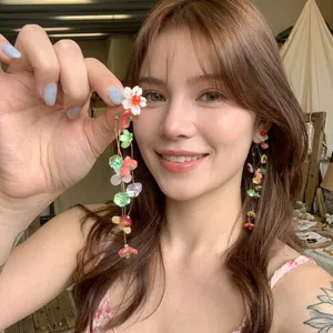 Close-up of handmade colorful floral tassel earrings worn by a model in a casual setting