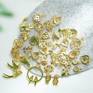 Detailed close-up of 18K gold plated bird, evil eye, and heart charms with zircon inlay