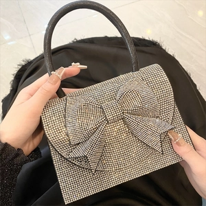 Close-up of elegant silver rhinestone evening bag with a large sparkling bow and handle