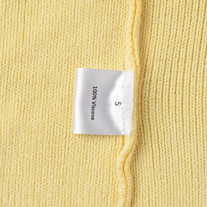 Detail view of ginger yellow knitwear showing 100% Viscose care label and soft texture