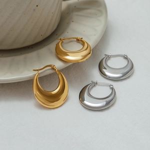 Polished 18K gold and silver stainless steel hoop earrings on a white tabletop display