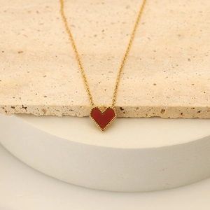 Macro shot of 18k gold-plated red heart necklace pendant with detailed perlée edging