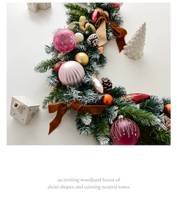 Detail of Christmas garland with pink ornaments, pine cones, and velvet bows with snow