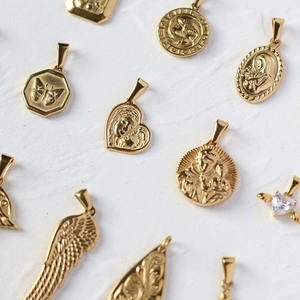 Detailed flat lay of assorted 18K gold plated pendants with religious and heart motifs