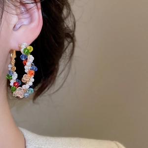 Detail of colorful crystal beads and pearls hand-wrapped on gold hoop earrings for women