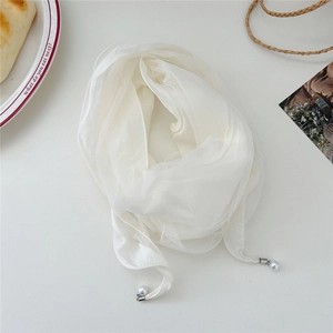 Close-up of white lace scarf with elegant pearl charms on a stylish background