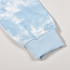 Dettaglio del tessuto tie-dye azzurro e dei polsini a costine elastici sulla maglia a maniche lunghe