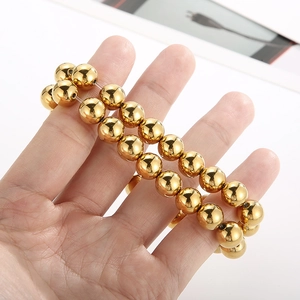 Detail of high-polish gold beaded stretch bracelets with metallic mirror finish
