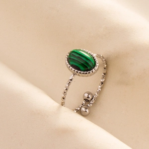 Macro shot of silver adjustable ring with malachite stone on satin fabric