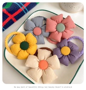 Detail of 5-pack floral fabric hair ties in assorted colors displayed on a white plate