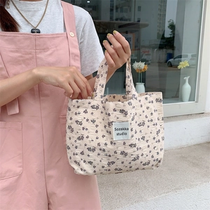 Close-up of vintage floral canvas tote featuring purple flowers and a brand logo tag