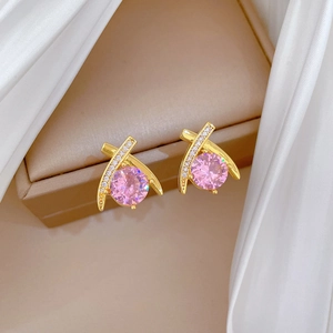 Close-up of gold-plated cross design earrings with pink gemstone and zircon in a gift box