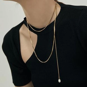 Close-up of golden double-layer snake chain necklace featuring a delicate pearl pendant
