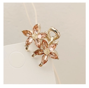 Detailed close-up of golden floral hair claw with pink crystals and shimmering petals
