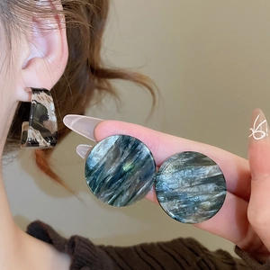 Détail de boucles d'oreilles géométriques en acrylique à motif écaille de tortue et clous