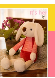 Detailed close-up of a white plush rabbit wearing red striped overalls on a textile mat