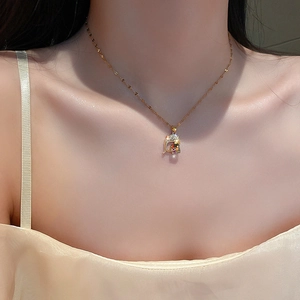 Golden dolphin cube pendant necklace with iridescent crystal on model's neck