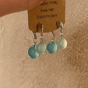 Detail view of two pairs of elegant cyan resin teardrop earrings on a display card