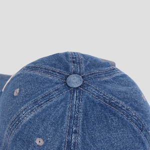 Close-up of denim baseball cap crown showing reinforced stitching and button top