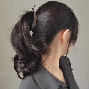 Brown plastic hair claw clip securing a ponytail on model with a natural look