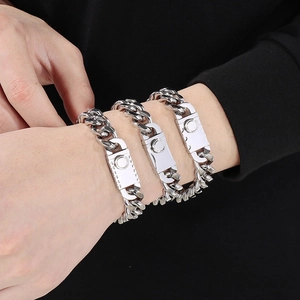 Macro shot of silver-colored stainless steel Cuban link bracelets with textured clasps