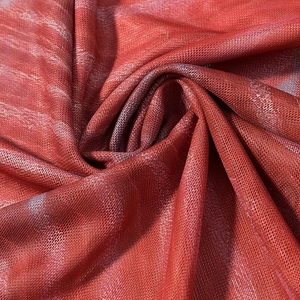 Détail du tricot en maille rouge avec motif tie-dye et texture fine respirante