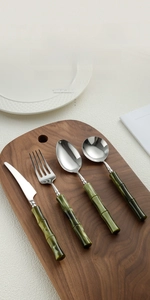 Detail of 304 stainless steel cutlery set with green bamboo-shaped resin handles on wood