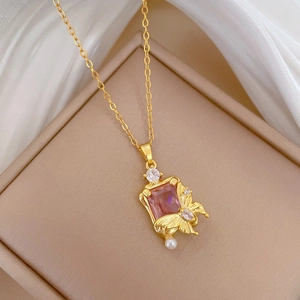 Detail of gold butterfly necklace with pink gemstone and small pearl on silk background
