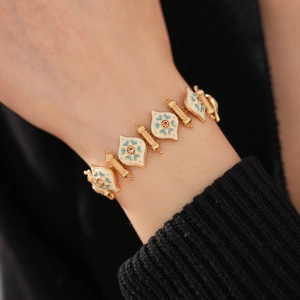 Detail of vintage gold bracelet with white enamel leaf charms and turquoise floral motifs