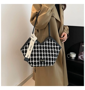 Detail of checkered tote bag with fashion metal logo and stylish fabric tag accessory