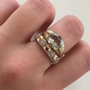 Detail of 18k gold plated ring set with green oval gemstone and pavé stones on hand