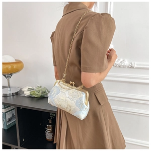 Detail of light blue floral jacquard handbag with gold metal clasp and chain strap