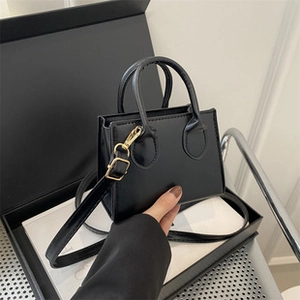 Detail of a chic black square crossbody bag with gold hardware and dual handles