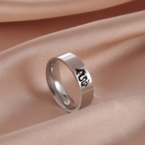 Dettaglio ravvicinato di un anello in acciaio con motivo a drago su tessuto di seta color champagne