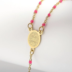 Macro view of Saint Benedict medal with pink beads on a golden stainless steel chain