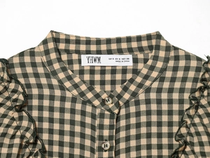 Detailed close-up of the round neckline and buttons on the plaid long sleeve shirt