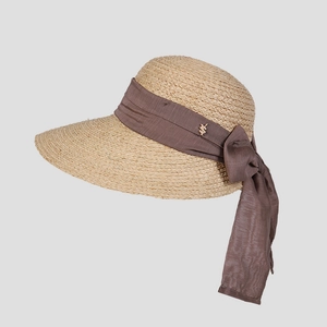 Détail d'un chapeau de paille en raphia avec ruban marron et pendentif doré