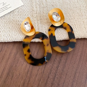 Detail of tortoise shell acrylic earrings with gold metal base and clear crystal stone