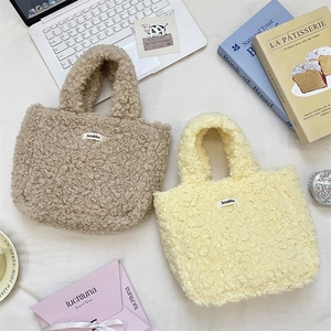 Flat lay of small plush tote bags in camel and yellow with cozy lifestyle props