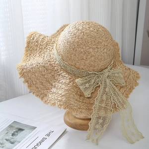 Dettaglio del cappello di paglia in rafia con fiocco decorativo in pizzo floreale