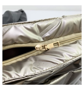 Close-up of metallic puffy tote bag featuring premium gold zipper and quilted stitching